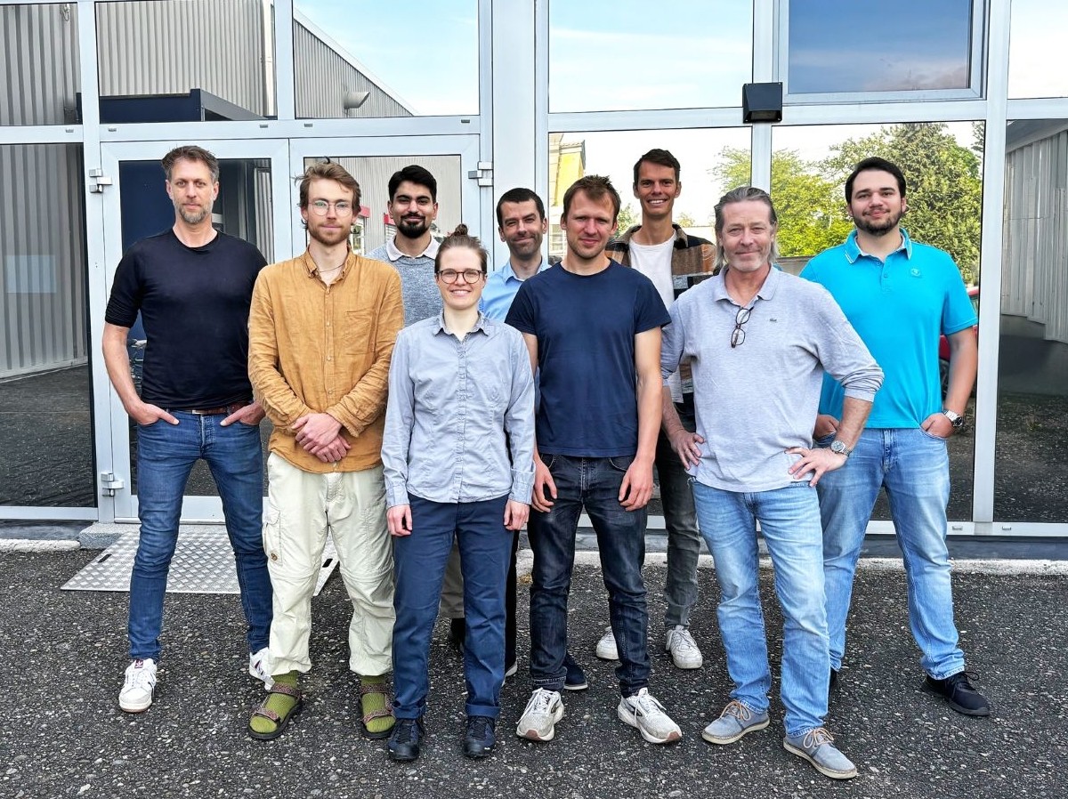 A photo of nine scientists and innovators smiling outside their new company headquarters